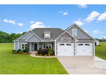 Beautiful home exterior with manicured lawn, gray siding, stone accents, and a three-car garage at 210 Dorothy Dr, China Grove, NC 28023