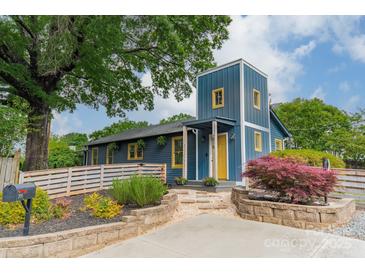 Charming blue two-story home featuring a yellow door, beautiful landscaping and a lush green tree canopy at 2915 Wesley Ave, Charlotte, NC 28205
