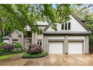 Stunning stone and shingle home with a two-car garage, complemented by lush landscaping and mature trees at 3932 Rounding Run Rd, Charlotte, NC 28277