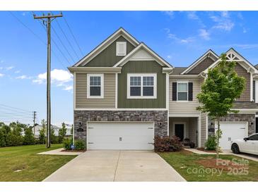 Inviting townhome featuring a stone-accented front, two-car garage, and a well-manicured lawn at 5207 Maynard Hill Dr, Monroe, NC 28110