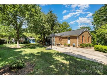 Charming single-story brick home with a lush lawn, basketball hoop, and blue storage shed at 8544 Houston Ridge Rd, Charlotte, NC 28277