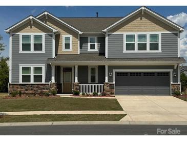 Charming two-story home with a covered front porch and a two-car garage, complete with a landscaped yard at 1119 Bellshill Dv, Indian Trail, NC 28079