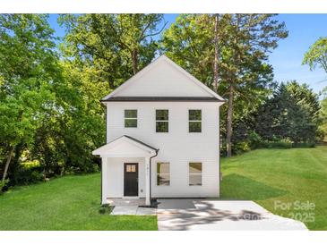 Charming two-story home featuring white siding, a welcoming front porch, and a well-maintained lawn surrounded by mature trees at 1411 Duhart Ave, Gastonia, NC 28054