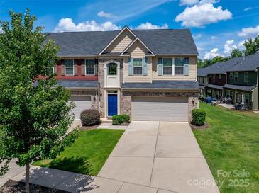 Charming townhome with blue door, brick accents, garage, and well-manicured lawn under a bright, partly cloudy sky at 1769 Evergreen Dr, Charlotte, NC 28208