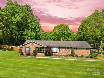 Charming brick ranch home features a lush lawn, mature trees, and a welcoming front entrance at 245 Kingsway Cir, Charlotte, NC 28214