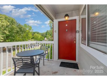 Inviting balcony with a table and chairs and bright red front door offering a place to sit and enjoy the view at 3201 Heathstead Pl # C, Charlotte, NC 28210