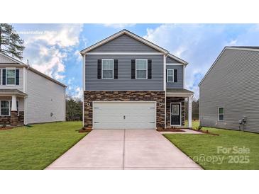 New two-story home boasts gray siding, stone accents, a two-car garage, and a well-manicured lawn at 581 E Sparkleberry St, Chester, SC 29706
