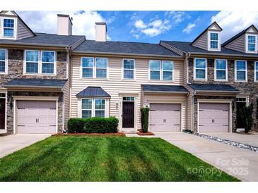 Charming townhome with a well-manicured lawn, attached garage, and stone accents at 9614 Springholm Dr, Charlotte, NC 28278