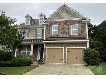 Two-story home showcasing a blend of stone and siding with a two-car garage and well-manicured lawn at 10817 Bere Island Dr, Charlotte, NC 28278
