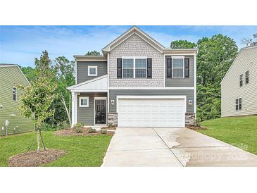 Charming two-story home featuring a stone-accented facade, a two-car garage, and manicured landscaping at 126 Dorian Pl, Troutman, NC 28166