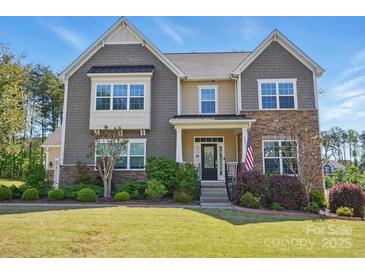 Beautiful two-story home featuring stone and shingle siding, manicured lawn, and an inviting front porch at 16831 Alydar Commons Ln, Charlotte, NC 28278