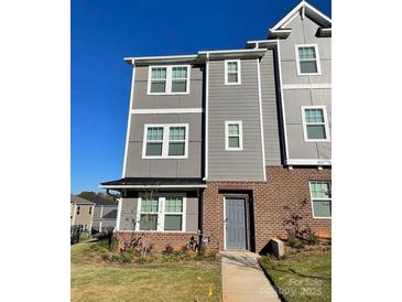 Three-story townhouse featuring gray siding, brick accents, and well-maintained landscaping at 2019 Tears Ln, Charlotte, NC 28217