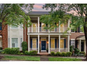 Charming two-story brick home with a welcoming front porch and balcony, surrounded by lush landscaping and mature trees at 239 N Faulkner Way, Davidson, NC 28036