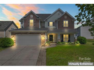 Charming two-story home featuring a stone-accented facade, well-manicured lawn, and attached two-car garage at 9639 Ravenscroft Nw Ln, Concord, NC 28027