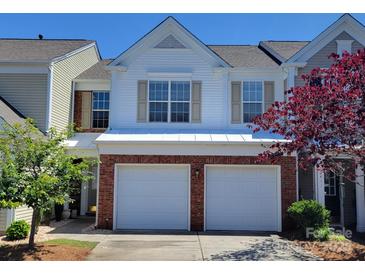 Charming two-story townhouse featuring a two-car garage, brick accents, and a well-manicured front yard on a sunny day at 12407 Crowley Ct, Charlotte, NC 28277