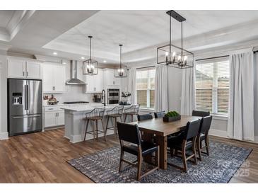 Bright, open kitchen features white cabinets, stainless steel appliances, and an island with barstool seating at 1634 Dresden Dr, Rock Hill, SC 29732