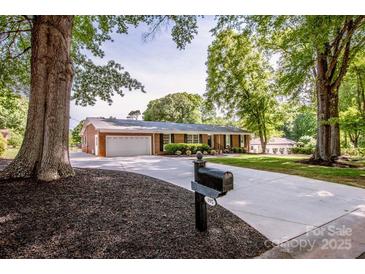 Charming brick home featuring mature trees, a two-car garage, and a long, paved driveway at 195 Brookfield Cir, Mooresville, NC 28115
