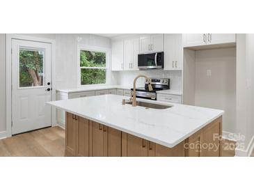 Bright kitchen with white cabinets, stainless steel appliances, and large island with quartz countertop at 4042 Uppergate Ln, Charlotte, NC 28215