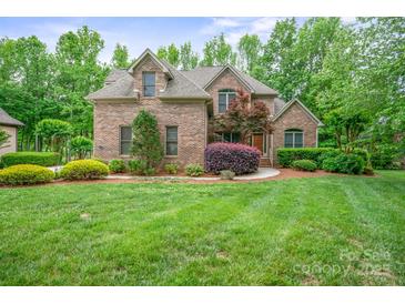 Charming brick home with lush landscaping and mature trees in a serene, picturesque setting at 8216 Malibu Pointe Ln, Denver, NC 28037