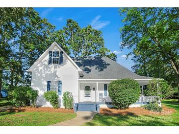 Charming white farmhouse with blue shutters, lush landscaping, and a welcoming front porch at 108 Stockton St, Shelby, NC 28150