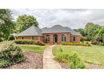 Charming brick home with manicured lawn, arched windows, and a welcoming walkway to the front door at 1337 Braeburn Nw Rd, Concord, NC 28027