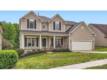 Charming two-story home features a welcoming front porch, manicured lawn, and attached two-car garage at 1455 Moss Creek Dr, Harrisburg, NC 28075