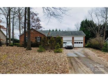 Charming one-story brick home with a two-car garage and mature trees on a leaf-covered lawn at 4424 Huntington Dr, Gastonia, NC 28056