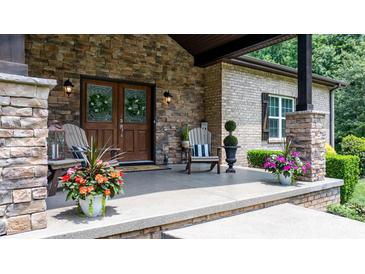 Charming front porch featuring stone pillars, wood doors, and decorative plants, creating a welcoming entrance at 4616 Gold Finch Dr, Denver, NC 28037