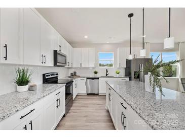 A modern kitchen featuring white cabinets, stainless steel appliances, and a large center island with granite countertops at 515 Dixie Dr, Mooresville, NC 28115