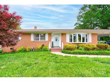 Charming brick home with well-manicured lawn, flowering bushes, and a welcoming front porch at 109 Ashley St, Shelby, NC 28150