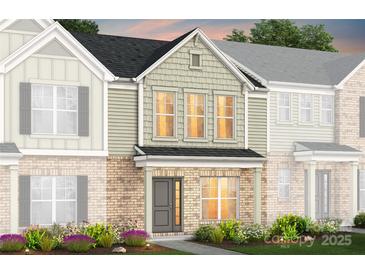 Charming townhome with brick facade, gray door, beautiful landscaping, and a welcoming entrance at 2207 Riverstone Blvd # 136, Monroe, NC 28110