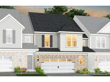 Charming townhome showcasing a brick and gray facade, complemented by a well-lit garage and manicured landscaping at 2211 Cobble Ct # 213, Monroe, NC 28110