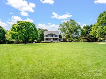 Charming two-story home with front porch and spacious lawn surrounded by mature trees on a sunny day at 4628 Dovefield Ln, Kannapolis, NC 28081