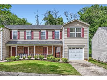 Charming townhome with a welcoming porch and attached garage, surrounded by lush landscaping and mature trees at 6335 Ziegler Ln, Charlotte, NC 28269