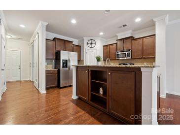 An open kitchen offers stainless steel appliances, granite countertops, and dark wood cabinets at 17916 Ragtop Day Ln, Cornelius, NC 28031