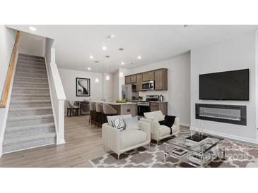 Open-concept living room with modern fireplace, luxury vinyl plank flooring, and an adjacent kitchen with an island at 2918 Sloan Dr, Charlotte, NC 28208