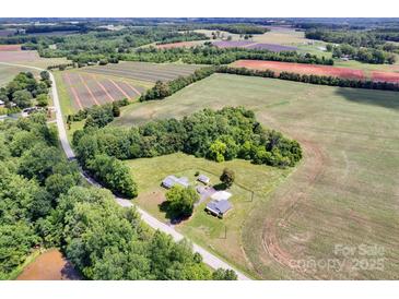 An aerial view showcases a property surrounded by lush farmland and verdant trees, blending rural charm and peaceful seclusion at 335&315 Graham Rd, Mt Ulla, NC 28125