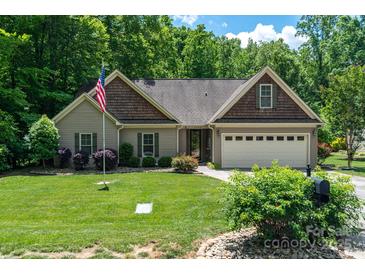 Charming single-story home with mature landscaping, an American flag, and a two-car garage at 6398 Winding Creek Ln, Denver, NC 28037
