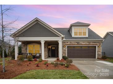 Charming single-story home featuring stone accents, a covered porch, and an attached two-car garage at 687 Poplar View Nw Dr, Concord, NC 28027
