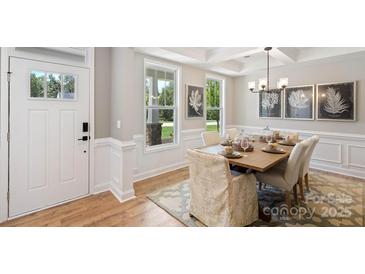 Inviting dining room boasts a modern chandelier, stylish decor, and a view of the landscaped outdoors at 7105 Butternut Oak Ter, Huntersville, NC 28078