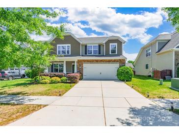 Two story home with neutral siding, brick accents, landscaping and two car garage at 7711 Kelburn Ln, Charlotte, NC 28273