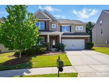 Charming two-story home boasts a brick and siding exterior, attached two-car garage, and a well-manicured front yard at 9301 Swimming Dr, Harrisburg, NC 28075