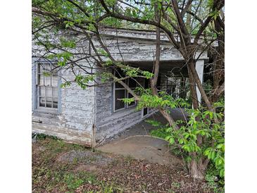 Distressed exterior with peeling paint, overgrown landscaping, and a covered porch at 1015 Frederick St, Shelby, NC 28150