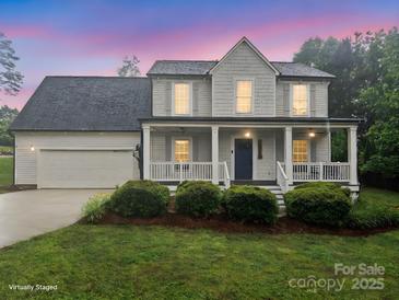 Charming two-story home with a covered porch, lush landscaping, and an attached two-car garage at 10749 Kingsview Dr, Davidson, NC 28036