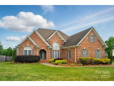 Charming brick home featuring manicured lawn and lush landscaping at 129 Daniel Efird Dr, Mount Holly, NC 28120