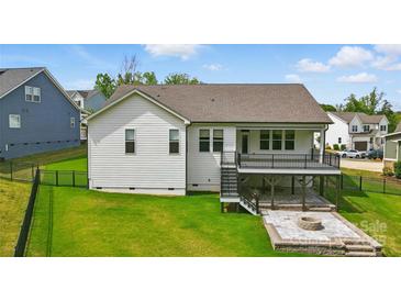 Beautifully landscaped backyard features a spacious deck, a stone patio, and a cozy fire pit at 4116 Spring Cove Way, Belmont, NC 28012