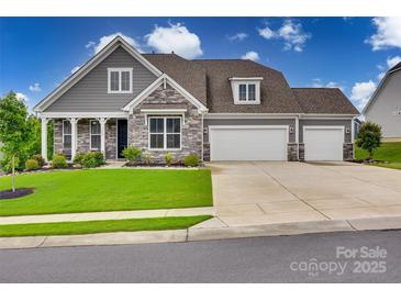 Charming two-story home featuring stone accents, a three-car garage, and a well-manicured lawn at 7049 Irongate Dr, Indian Land, SC 29707