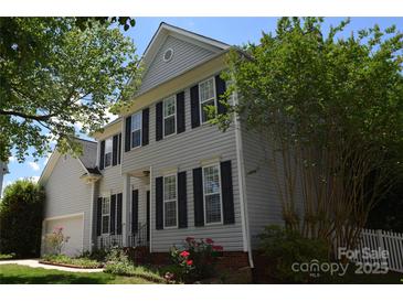 Charming two-story home with gray siding, black shutters, landscaped yard, and manicured greenery at 10434 Blackstock Rd, Huntersville, NC 28078