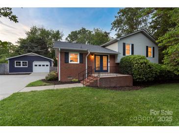 Quaint home with brick accents, a well-maintained lawn, and a detached garage at 15333 Catawba S Cir, Matthews, NC 28104