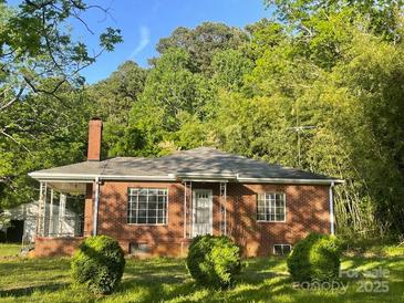 Charming brick home with a cozy front porch and well-maintained landscaping, set amidst lush greenery at 1835 Hollywood Dr, Salisbury, NC 28144